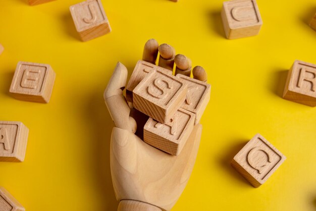 Wooden cubs with letters for words in wood hand on yellow background business and study concept top view