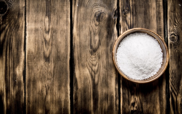 Wooden Cup with salt . On a wooden background.