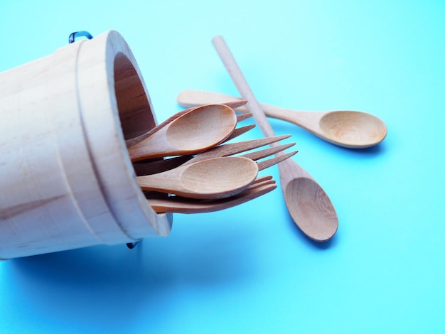 Above of wooden cutlery in bucket wooden spoon isolated on blue background