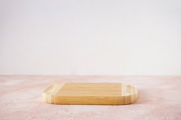 Wooden cutting board on a beige background with space for text.