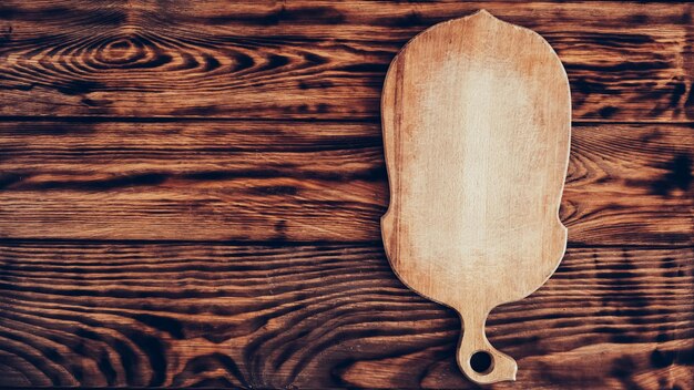 Wooden cutting board on brown table background