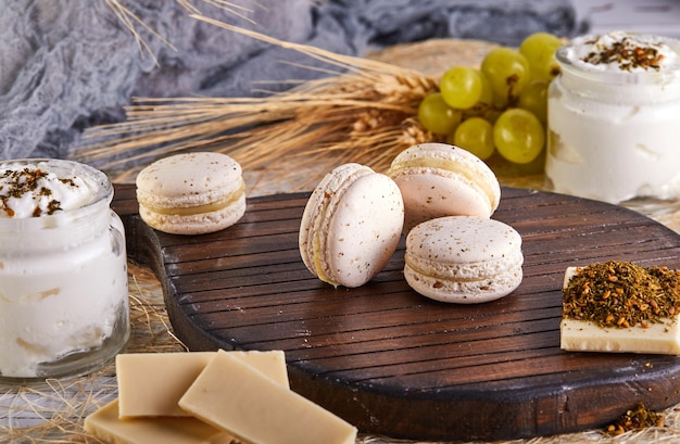 a wooden cutting board topped with macarons chocolate yogurt and grapes