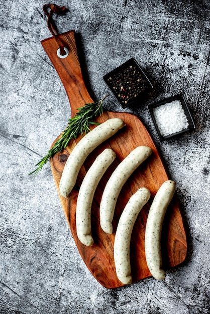 Photo a wooden cutting board with a bunch of sausages on it.