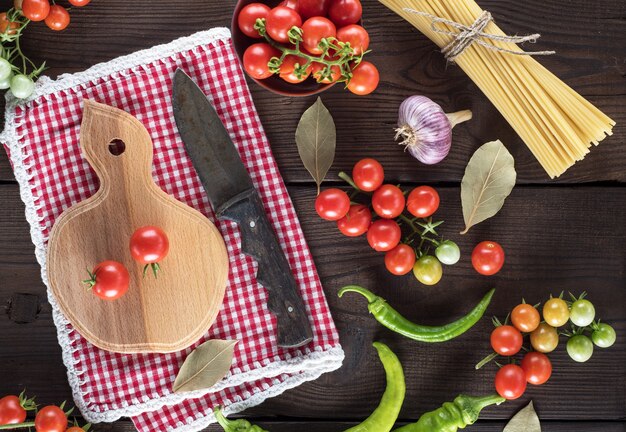 Wooden cutting board with a knife and fresh red cherry tomatoes