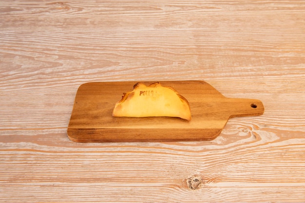 Photo a wooden cutting board with a piece of ravioli on it.