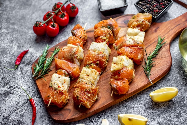 Foto un tagliere di legno con sopra un piatto di spiedini di salmone alla griglia.