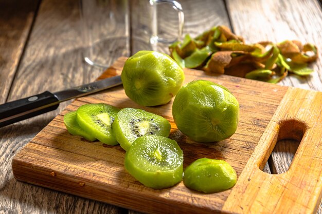 A wooden cutting board with sliced kiwis on it.