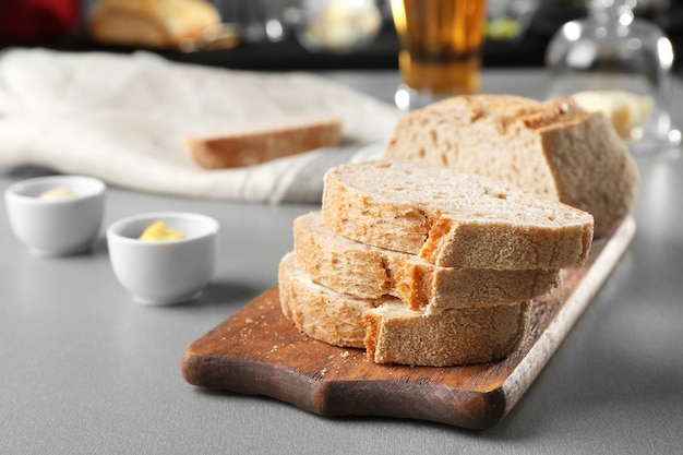 Wooden cutting board with sliced loaf of beer bread on table