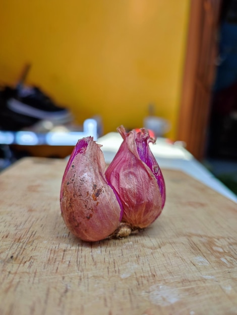 A wooden cutting board with two red onions on it.