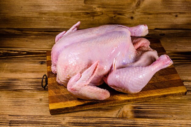 Wooden cutting board with the whole uncooked chicken