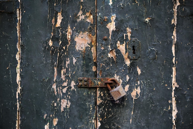 Photo wooden dark grey door background locked with rusty padlock aged entrance close up view with details