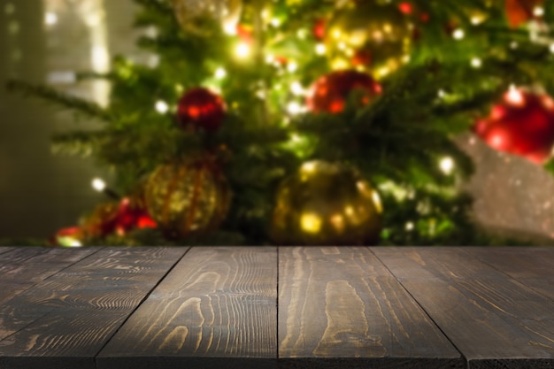 Wooden dark tabletop and blurred christmas tree bokeh. Xmas background for display or montage your products.