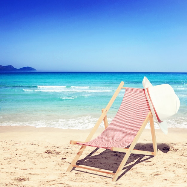 Foto sedie a sdraio in legno sulla spiaggia di sabbia vicino al mare. sfondo vacanza.