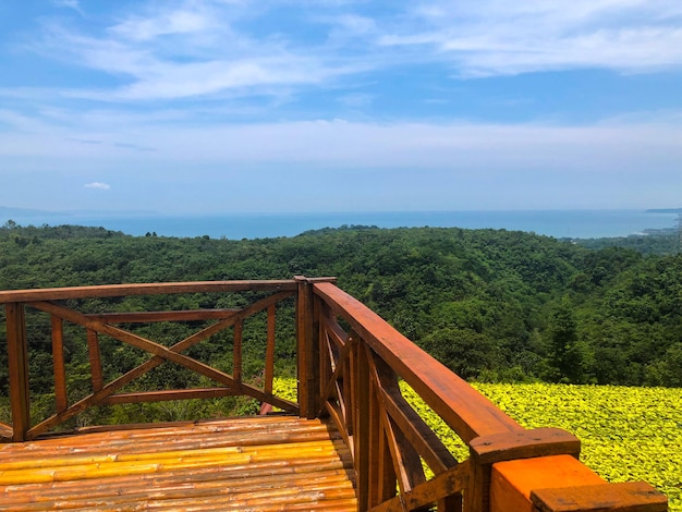 A wooden deck overlooking a green valley with a view of the ocean.