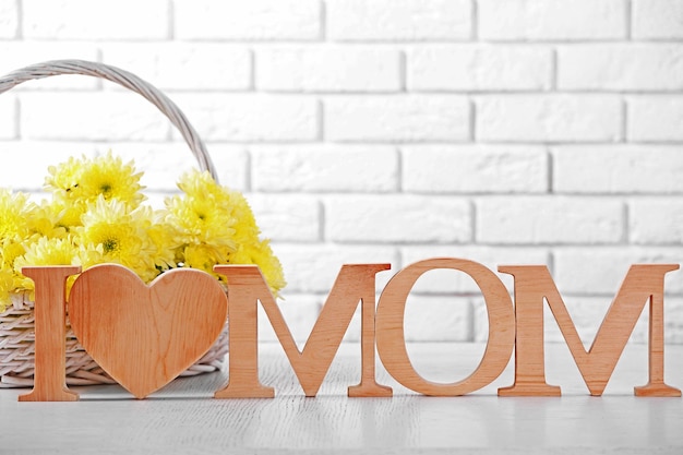 Wooden decor and flowers for mother's day on brick wall background