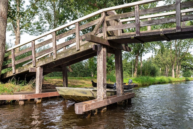 Foto ponte pedonale decorativo in legno su un canale nei paesi bassi sullo sfondo di piante e edifici