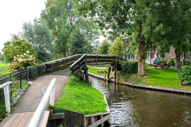 Foto ponte pedonale decorativo in legno su un canale nei paesi bassi sullo sfondo di piante e edifici