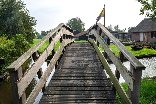 Foto ponte pedonale decorativo in legno su un canale nei paesi bassi sullo sfondo di piante e edifici