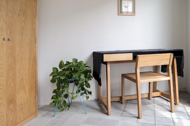 Wooden desk with chair plants in the room natural sunlight coming in pasta tile floor white painted walls