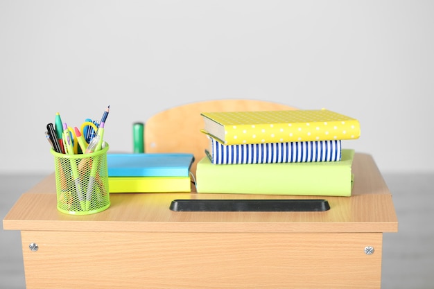 Photo wooden desk with stationery and chair in class on blackboard background