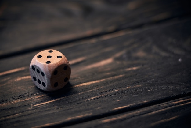 Wooden dice on old wood table. number five on the top side.