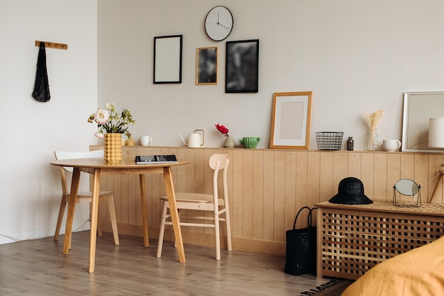 Деревянный обеденный стол в ярком домашнем интерьере. На столе лежат пионы в дизайнерской желтой вазе.