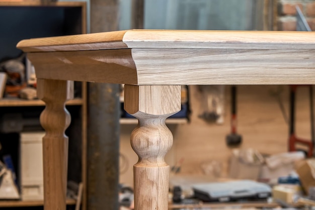 Wooden dining table with carved leg of solid oak and metal frame build process in workshop closeup