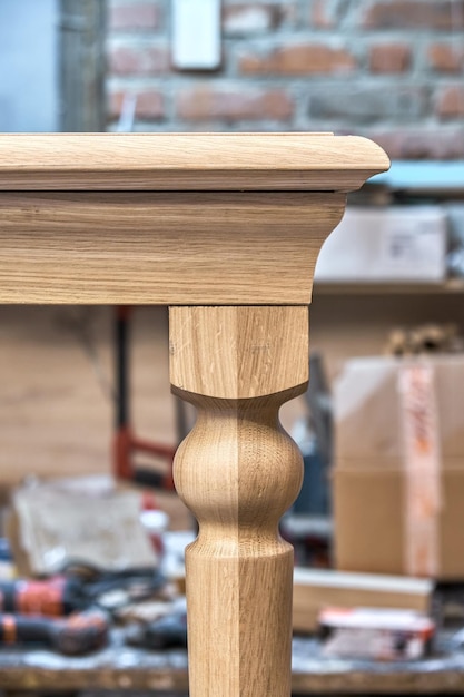 Wooden dining table with carved leg of solid oak and metal frame build process in workshop closeup