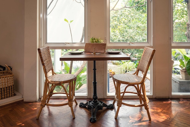 Wooden dining table with rattan chair and cutlery at beside window in restaurant