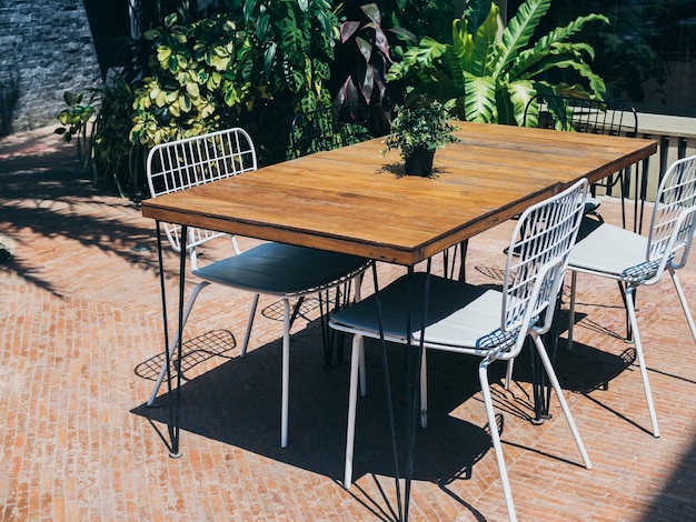 Wooden dining table with white chairs in the outdoor garden