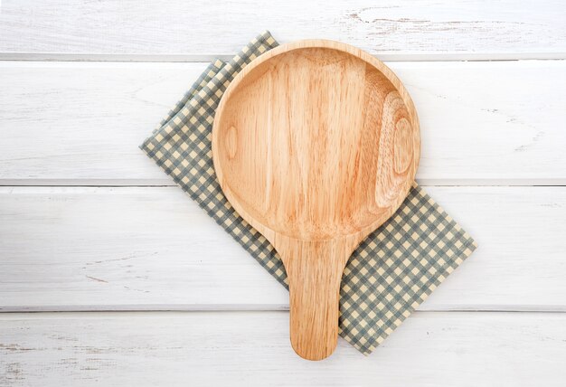Wooden dish board on napkin placed on the white wooden table 
