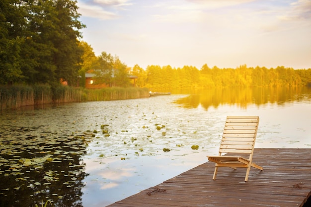 Photo wooden dock with lounge chair on pier on the calm lake in the middle of the forest