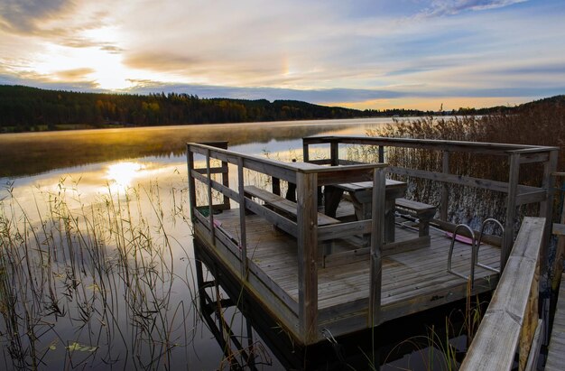 деревянный док с столом на берегу озера в сумерках в красивом ландшафте Швеции