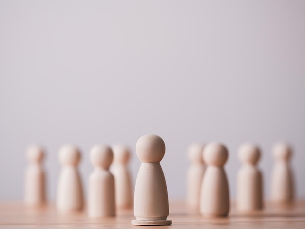 wooden doll or figure standing on wooden cube leading the team concept of leadership