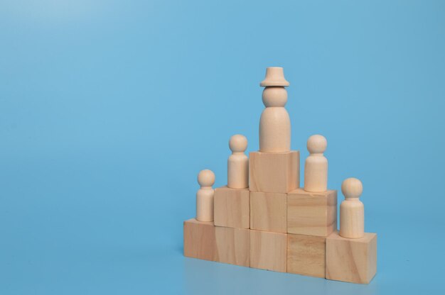 Wooden doll figures of businessman and office workers standing on wooden blocks Concept leader of the business team