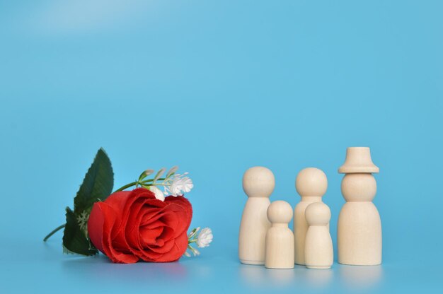 Wooden doll figures and red flower isolated on a blue background