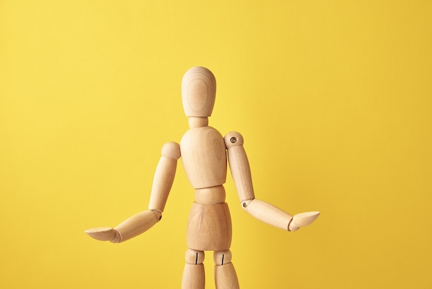 Photo wooden doll on yellow background