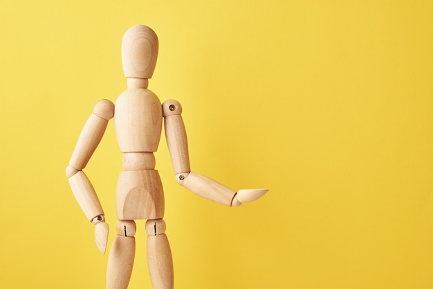 Wooden doll on yellow background