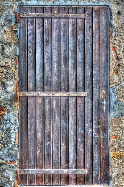 Photo wooden door in a rustic wall processed for hdr tone mapping effect