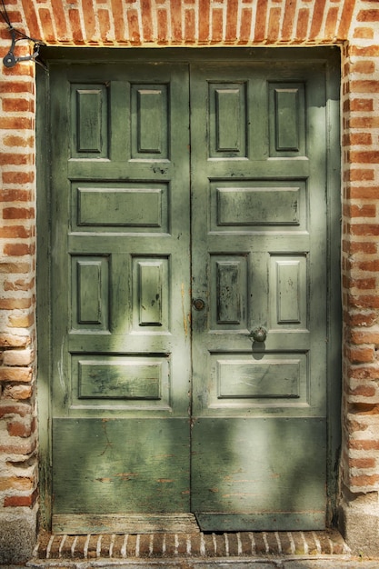 Photo a wooden door with green painted panels in a brown brick pathway