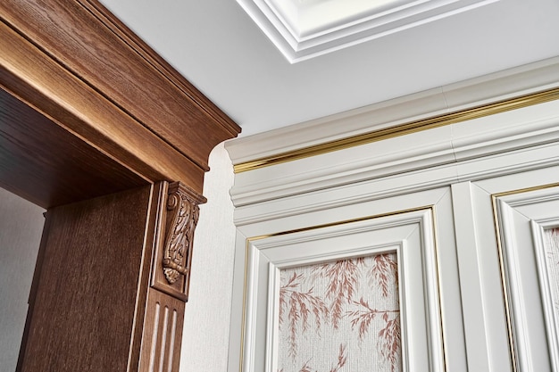 Wooden doorway with carved furniture brackets and fluted panel and wall panel with golden molding