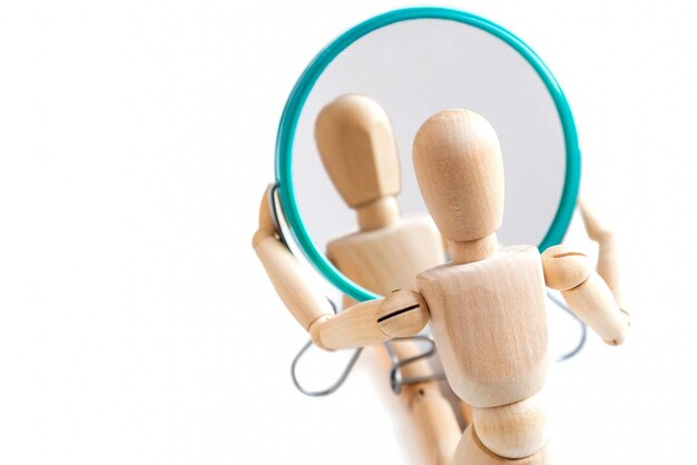 Wooden dummy looks at its reflection in the mirror