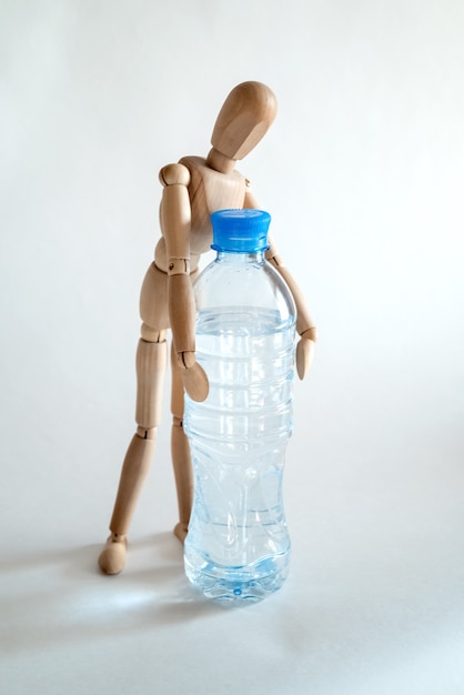 Wooden dummy picks up a plastic bottle of water