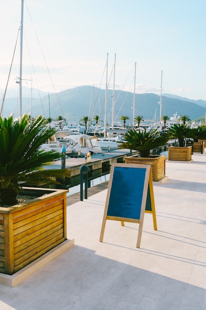 Wooden easel stands on the marina against parked white yachts