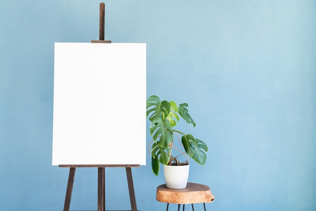 Wooden easel with blank canvas on light blue background for\
mockup design