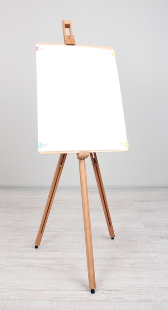 Wooden easel with clean paper in room