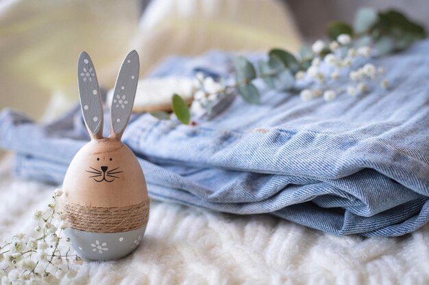 Photo a wooden easter egg sits on a bed with blue linens and a bunch of flowers.