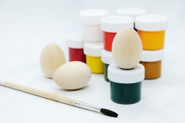 Wooden Easter eggs, multi-colored paints and brush for decorating souvenirs for celebration of Easter.