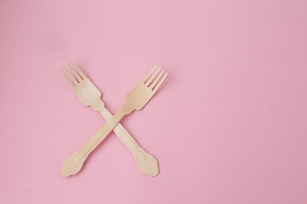 Wooden eco cutlery on a pink background full screen