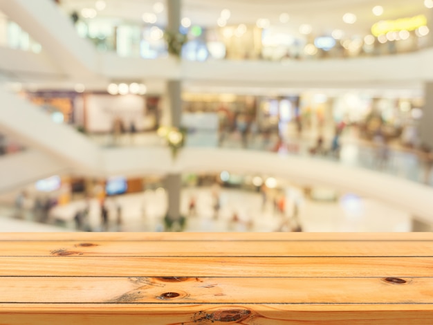 Wooden empty table blur in department store background.